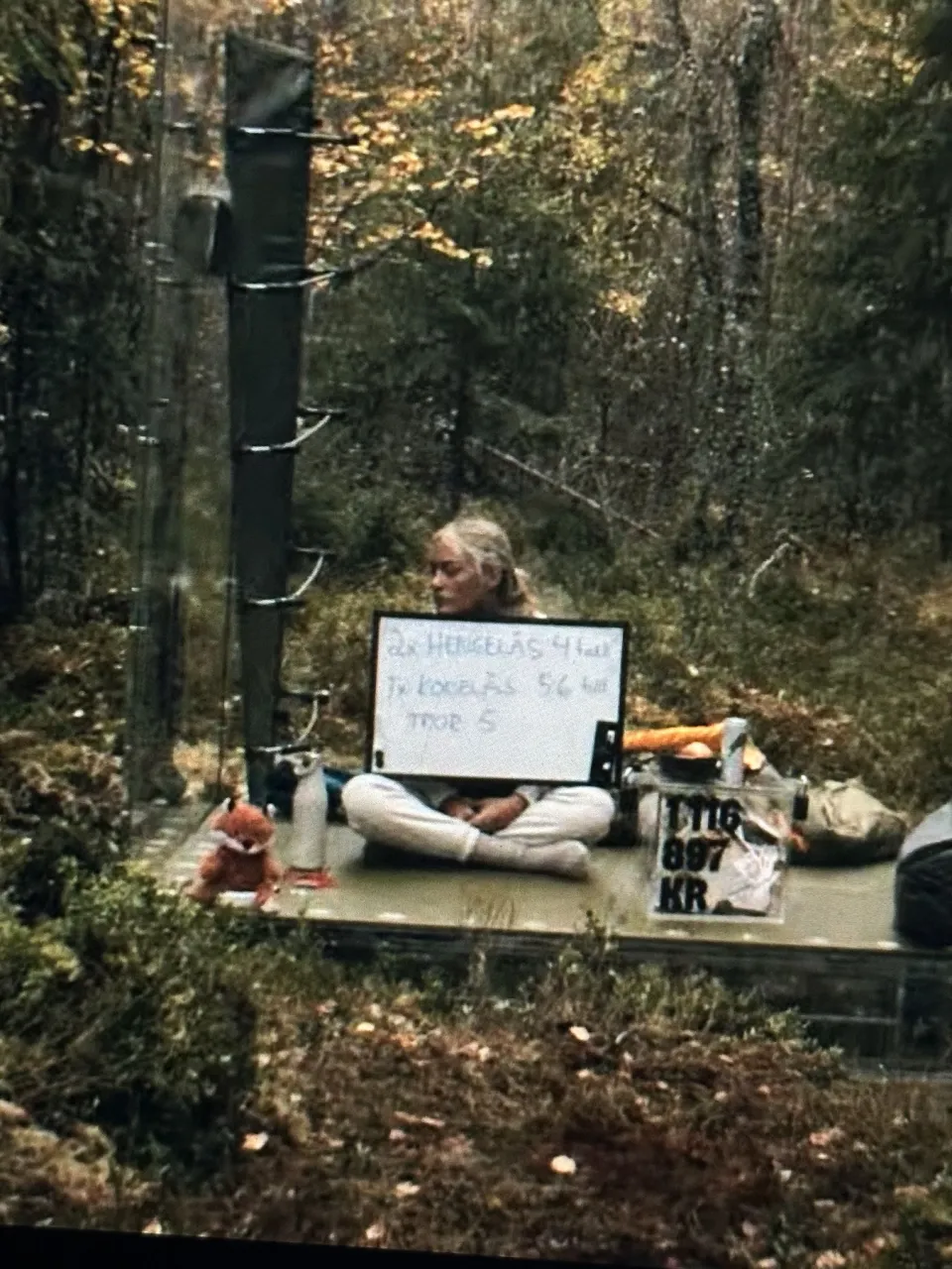 Deltakeren holder en tavle med beskjed om to hengelåser med fire sifre og én tallkode med fem eller seks sifre. Under står tror 5.